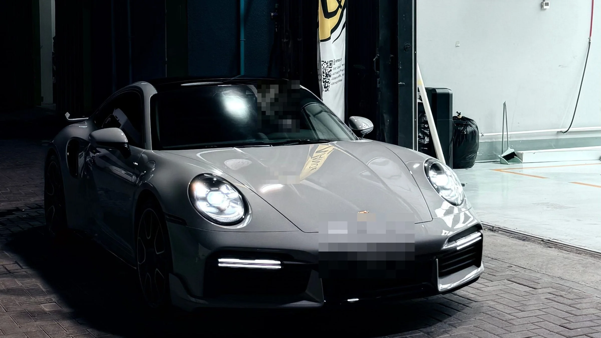 A grey Porsche 911 on the forecourt at night