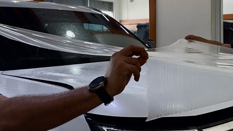 A full sheet of clear film lifted over the bonnet before it is laid