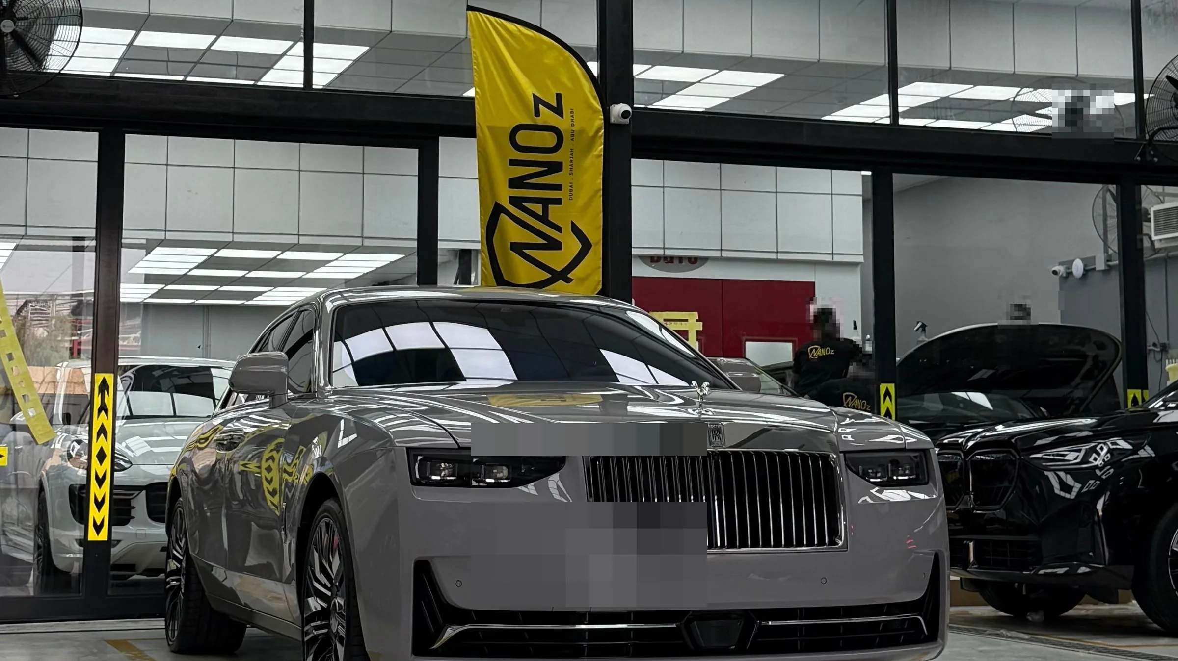 A grey Rolls-Royce Ghost facing the camera, the yellow flag rising behind