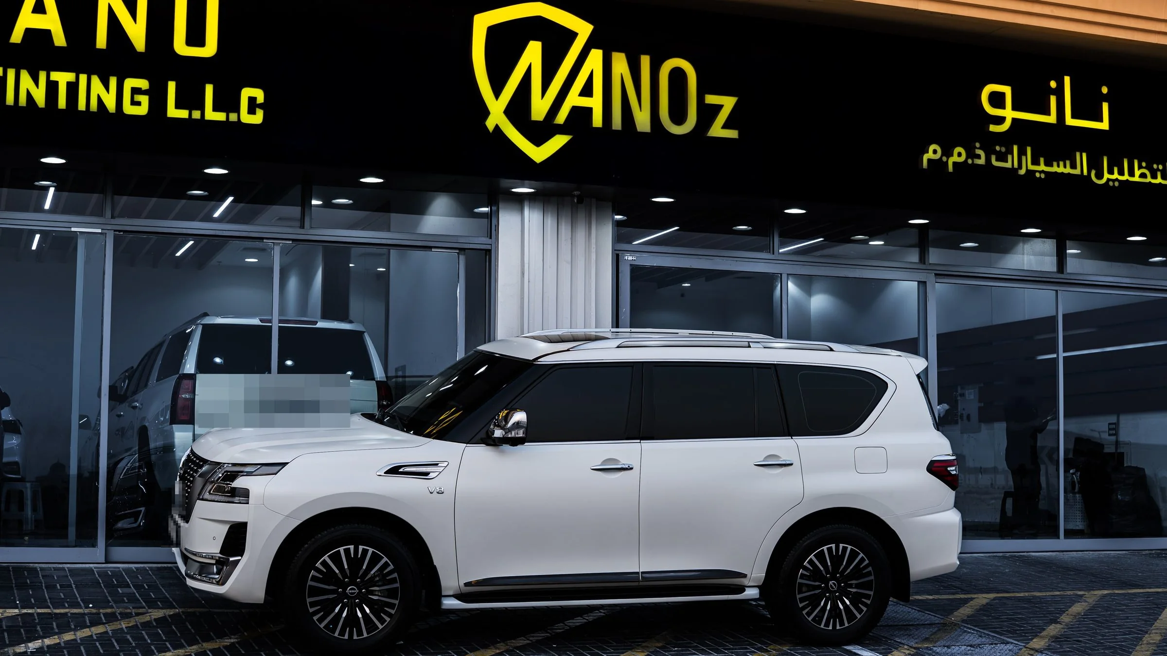 A white Nissan Patrol outside the Sharjah shopfront in the evening